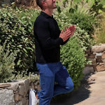 Man wearing long sleeve black open collar polo shirt with blue straight leg stretch jeans with classy style