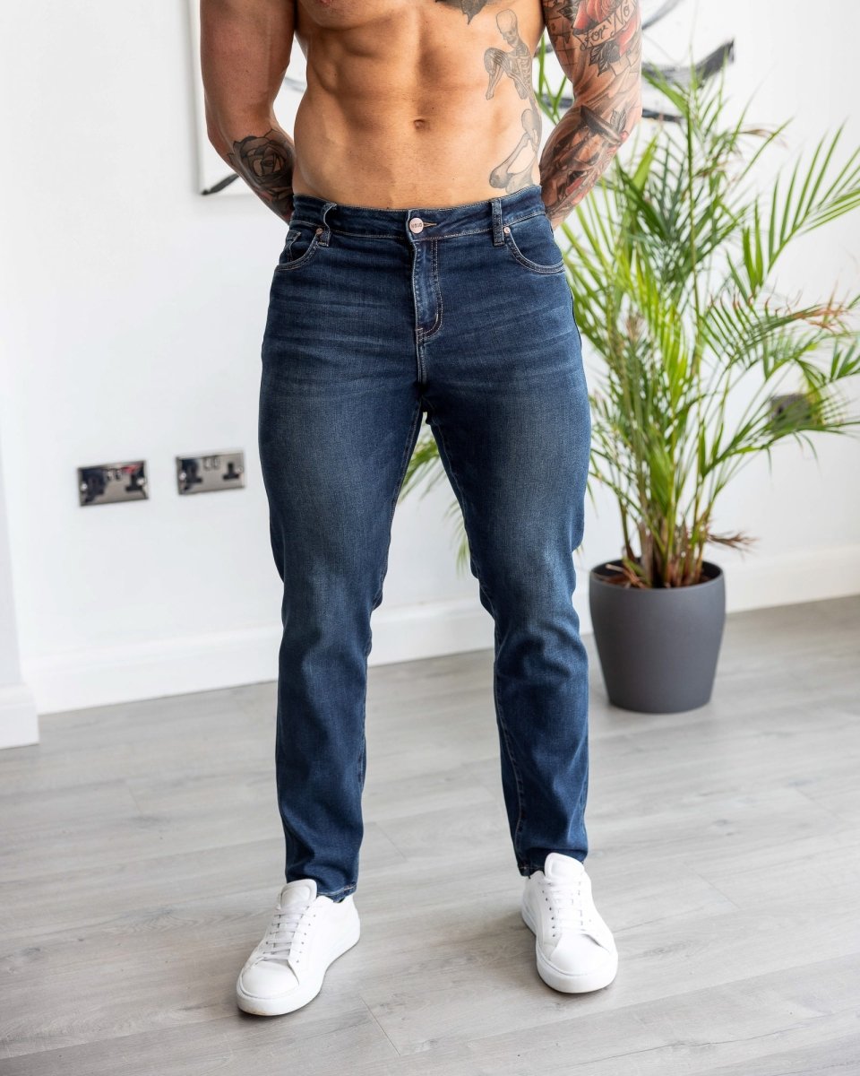 Bodybuilder Man with muscular build that has small waist and big thighs wearing kojo fit active tapered slim fit jeans