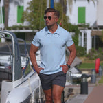 Man wearing light blue muscle fit polo and 5 inch dark gray chino shorts
