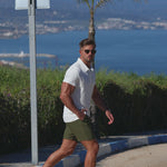 Man wearing stylish white slim fit polo and olive green chino dress shorts for smart casual summer outfit ideas by Kojo Fit