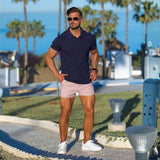 man wearing stylish smart casual outfit with navy blue slim fit polo and very short shorts in light pink