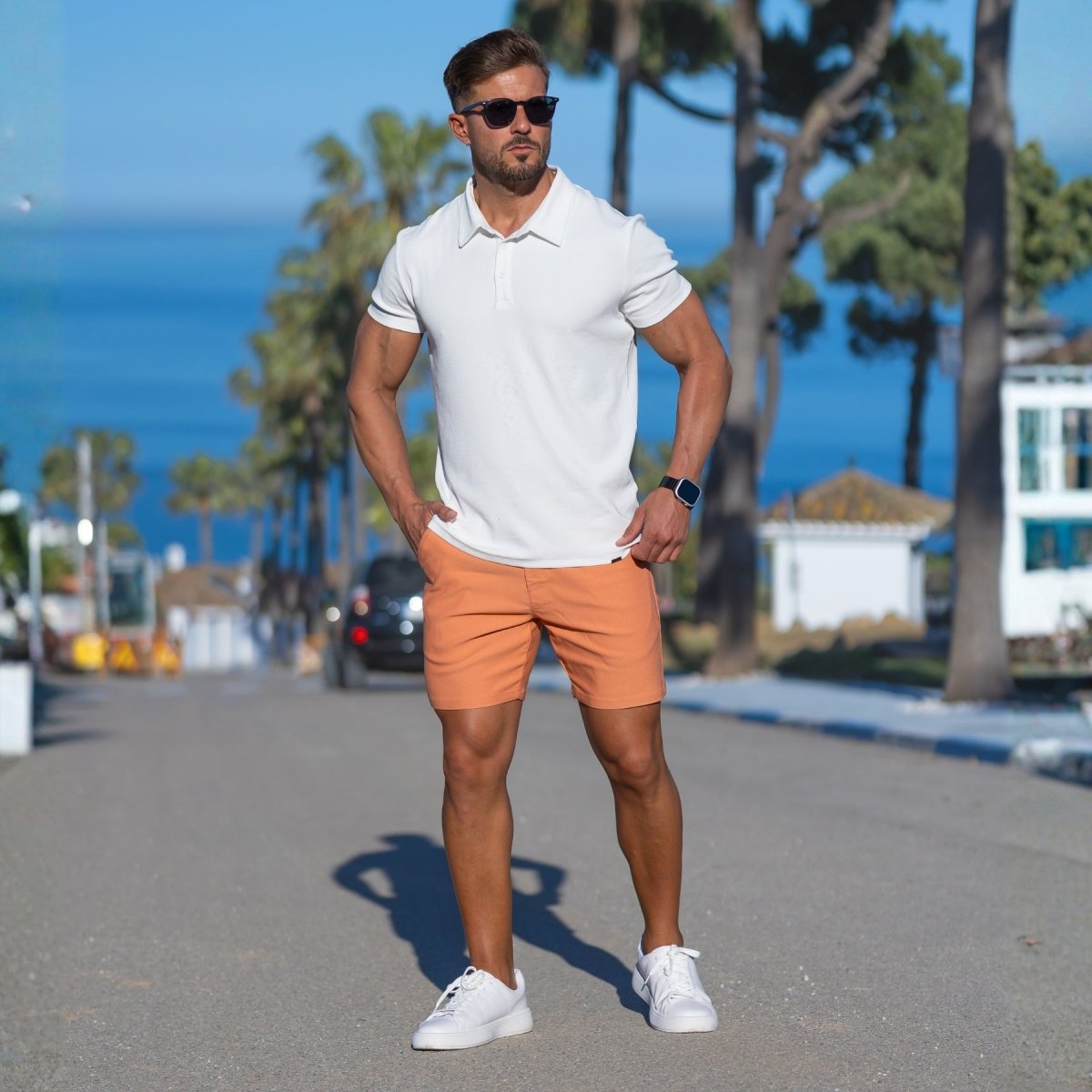 Man wearing white polo with coral orange casual shorts summer outfit style by Kojo Fit